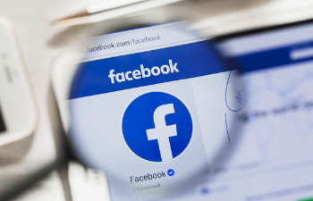 Facebook logo seen through a magnifying glass