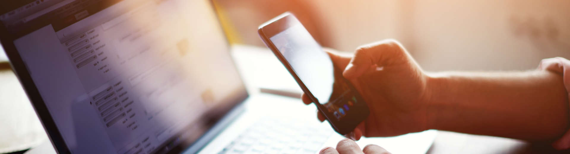 a person simultaneously looking at their smartphone and laptop screens