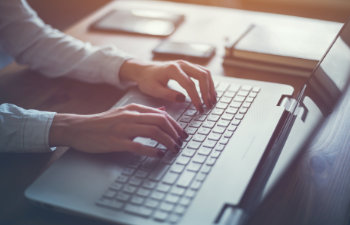 woman with red nails typing on the laptop keyboard